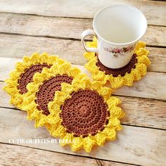 two crocheted sunflower coasters on a wooden table with a coffee cup