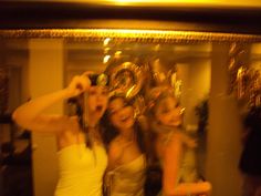 three women are posing for a photo in front of a mirror with gold decorations on it