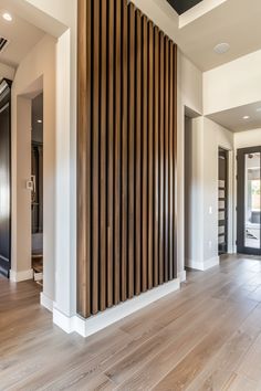 an empty room with wood slats on the wall and hard wood flooring in front of it