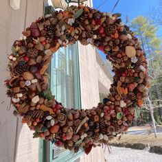 a wreath hanging on the side of a building with pine cones and acorns