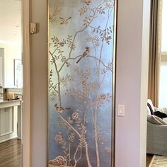 a large metal screen with birds and flowers on it in front of a living room door