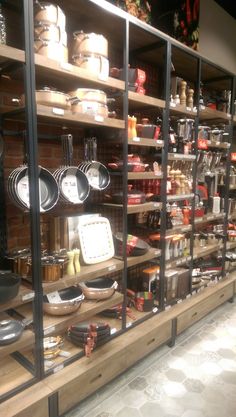 a display case filled with lots of pans and other kitchenware on wooden shelves