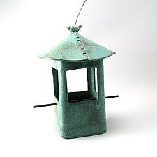 a small green bird feeder with a twig sticking out of it's top