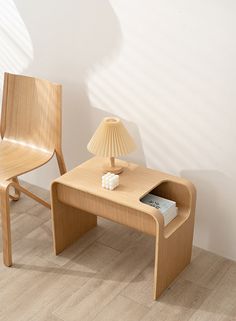 two wooden chairs sitting next to each other near a table with a lamp on it