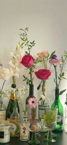 there are many bottles and vases with flowers in them on the table next to each other