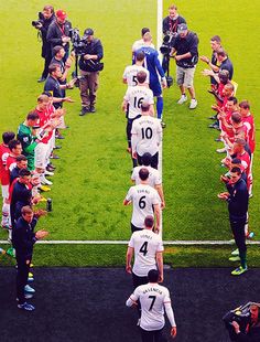 a group of men standing on top of a soccer field next to a crowd of people