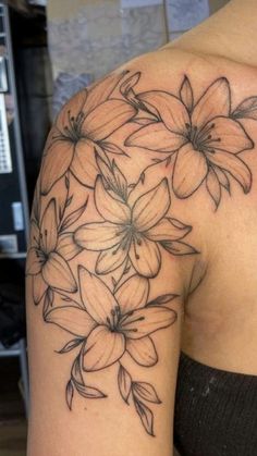 a woman's shoulder with flowers tattooed on the back of her left half - sleeve