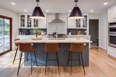 a large kitchen with two bar stools next to an island