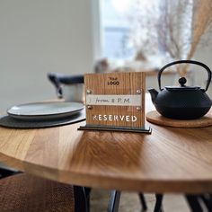 a wooden table with a tea pot and sign on it that says reserved next to a black teapot