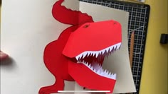 someone is making a paper dinosaur that looks like a t - rexe with its mouth open