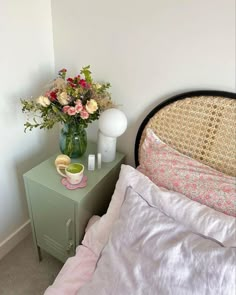 a green nightstand with flowers on it next to a bed