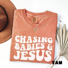 Super comfy shirt with a fun saying.  Chasing Babies and Jesus Comfort Colors Shirt makes a great gift. Comes in many different colors.  Makes a great "oversized" shirt to wear with leggings.    About Comfort Colors® 1717 T-shirt These ultra soft pigment dyed shirts are one of our best sellers, 100% Cotton. ⭐️ 100% ring spun cotton ⭐️ Preshrunk, soft-washed, garment-dyed fabric ⭐️ Set-in sleeves ⭐️ Double-needle stitched sleeves and bottom hem ⭐️ Twill taped shoulder-to-shoulder ⭐️ 1" ribbed col Cute Mom Shirts Vinyl, Diy Mom Shirts, Fun Mom Shirts, Christian Mom Shirts, Funny Cotton T-shirt With Lettering, Cricut Vinyl Shirts Ideas, Diy Cricut Shirts, Cute Shirt Designs Vinyl, Mom Shirts Vinyl