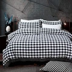 a black and white checkered comforter on a bed in a room with brick walls