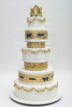 a four tiered cake with gold and blue decorations on the top, in front of a white background