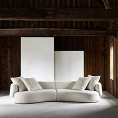 a white couch sitting in the middle of a room with wooden walls and flooring