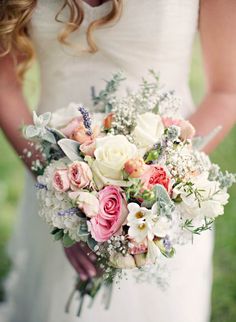 a bride holding a bouquet of pink and white flowers on her wedding day in the grass