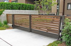 a wooden fence is shown in front of some bushes and trees on the side of a house