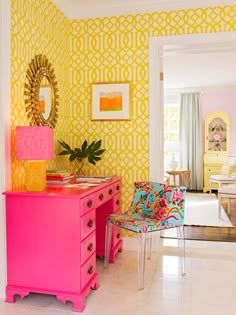 a pink dresser sitting in front of a mirror next to a yellow and white wall