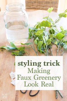 a wooden table topped with lots of green plants next to a jar filled with water