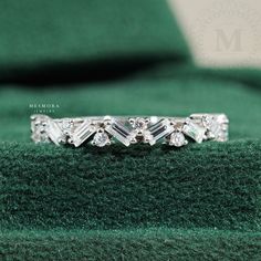 a diamond ring sitting on top of a green cushion