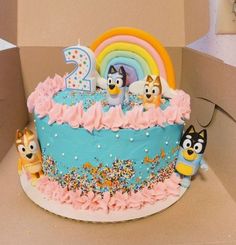 a birthday cake decorated with cartoon characters and sprinkles in a cardboard box