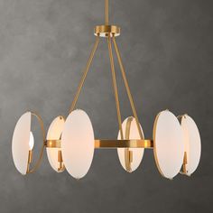 a brass chandelier with five white glass discs hanging from the middle of it