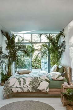 a bedroom with palm trees in the window and plants on the wall behind the bed