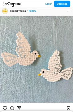 two white doves hanging from strings on a blue wall with an instagram message