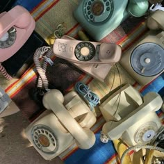 several old fashioned telephones sitting on top of a colorful tablecloth covered in different colors