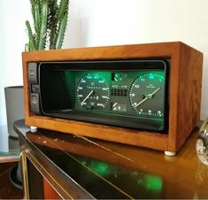 an old fashioned radio sitting on top of a wooden table next to a potted plant