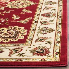 a red and white rug on the floor with an ornate border around it, in front of a wooden floor