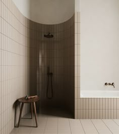 a white tiled bathroom with a stand up shower and bathtub next to a wooden stool