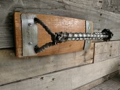 a metal hook on the side of a wooden wall with screws attached to it