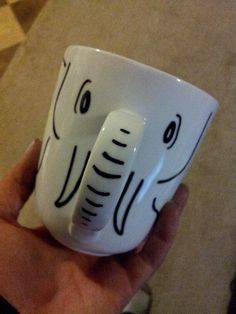 a hand holding a coffee cup with an elephant face on it