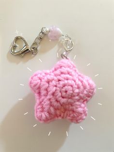 a pink crocheted star shaped keychain hanging from a chain on a white surface