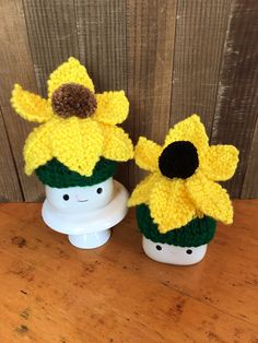 two knitted flower pots sitting on top of a wooden table