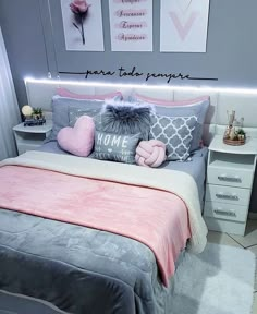 there is a bed with pink and gray pillows on it, along with two pictures above the bed