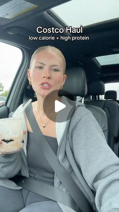 a woman sitting in the back seat of a car holding a drink and looking at the camera