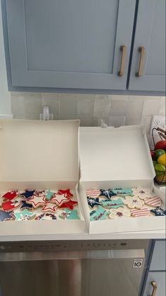 two open trays on top of a dishwasher in a kitchen with blue cabinets