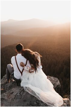 a bride and groom sitting on top of a mountain