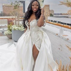 a woman in a wedding dress posing for the camera on a rooftop with tall buildings behind her