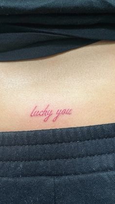 a woman's stomach with the words lucky you tattooed on her left side ribcage