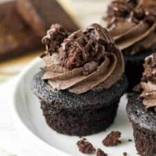 three chocolate cupcakes with frosting on a plate