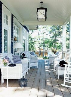 the porch is decorated with white wicker furniture and blue striped pillows, along with two chairs