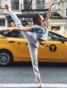 a woman is standing on one leg in front of a taxi while stretching her arm