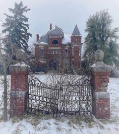 an old brick house with a gate in the front yard and snow on the ground