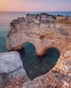 an ocean cliff with a small cave in the middle