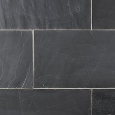 a black and white tile wall that has been made from dark grey marble tiles with thin lines