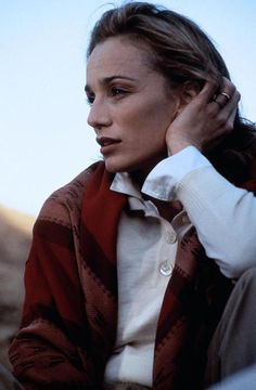 a woman sitting down with her hand on her ear and looking off into the distance