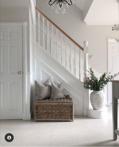 a basket with two pillows on the floor next to some stairs and a chandelier